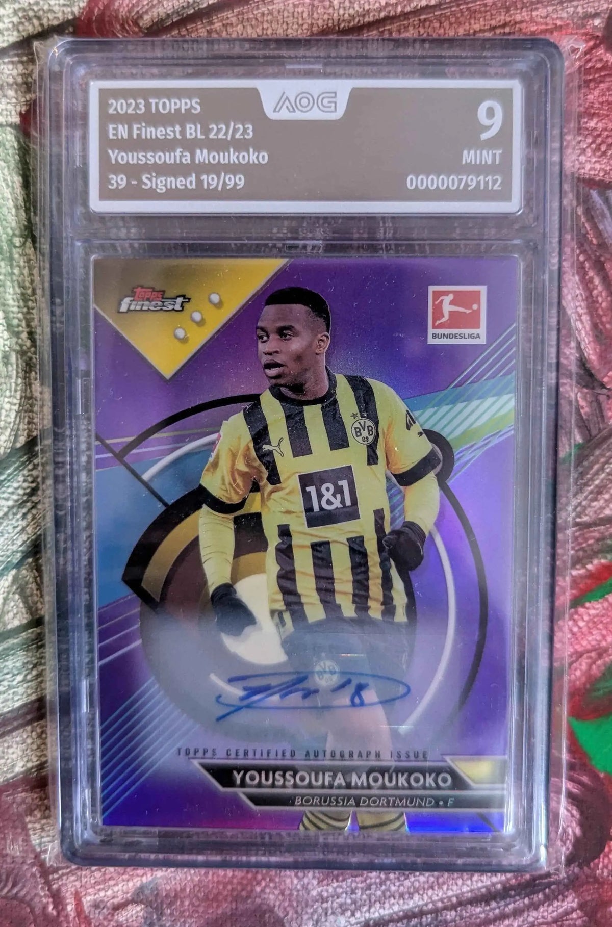 Ein signierte 2023 topps en finest baseballkarte von youssoufa moukoko in borussia dortmund trikot in klarer schutzhülle